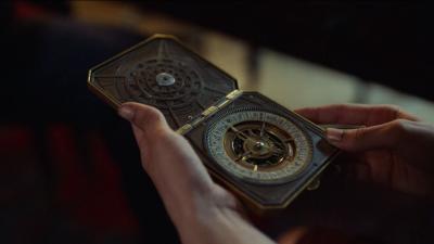 Image of an alethiometer being held in a person's hands.