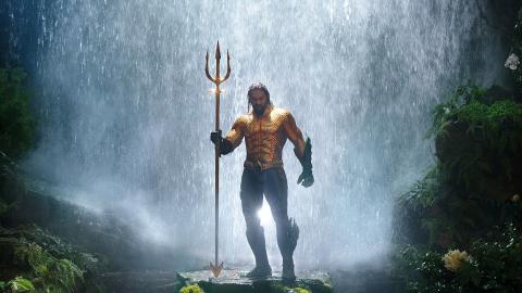 still from film, Jason Momoa as Aquaman, holding a trident and standing in front of a waterfall