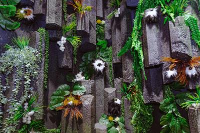 An installation that appears as a rocky surface with plants sprouting from its walls. 